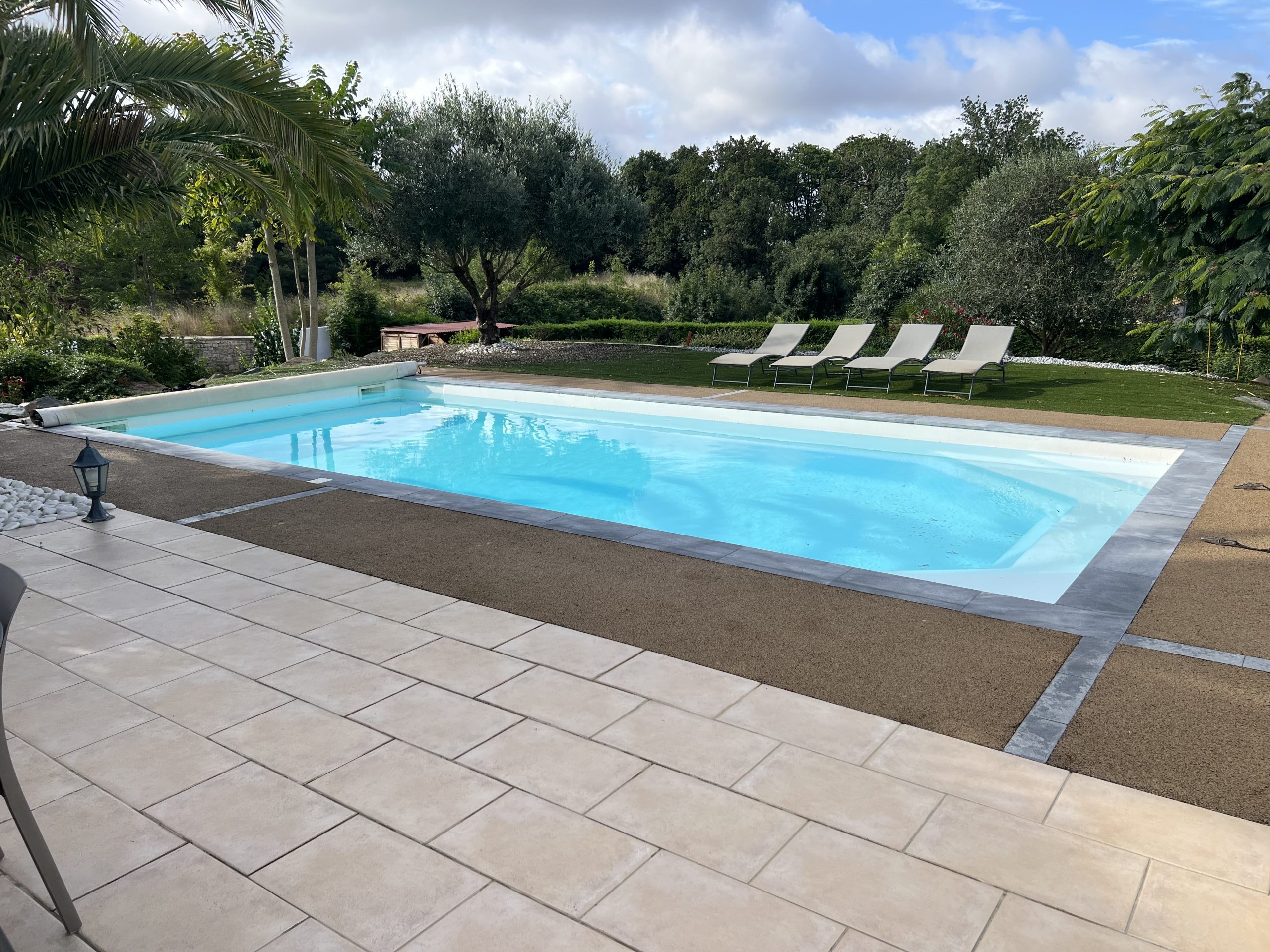 Création de bordure de piscine en béton poreux noir avec design de pavé blanc.